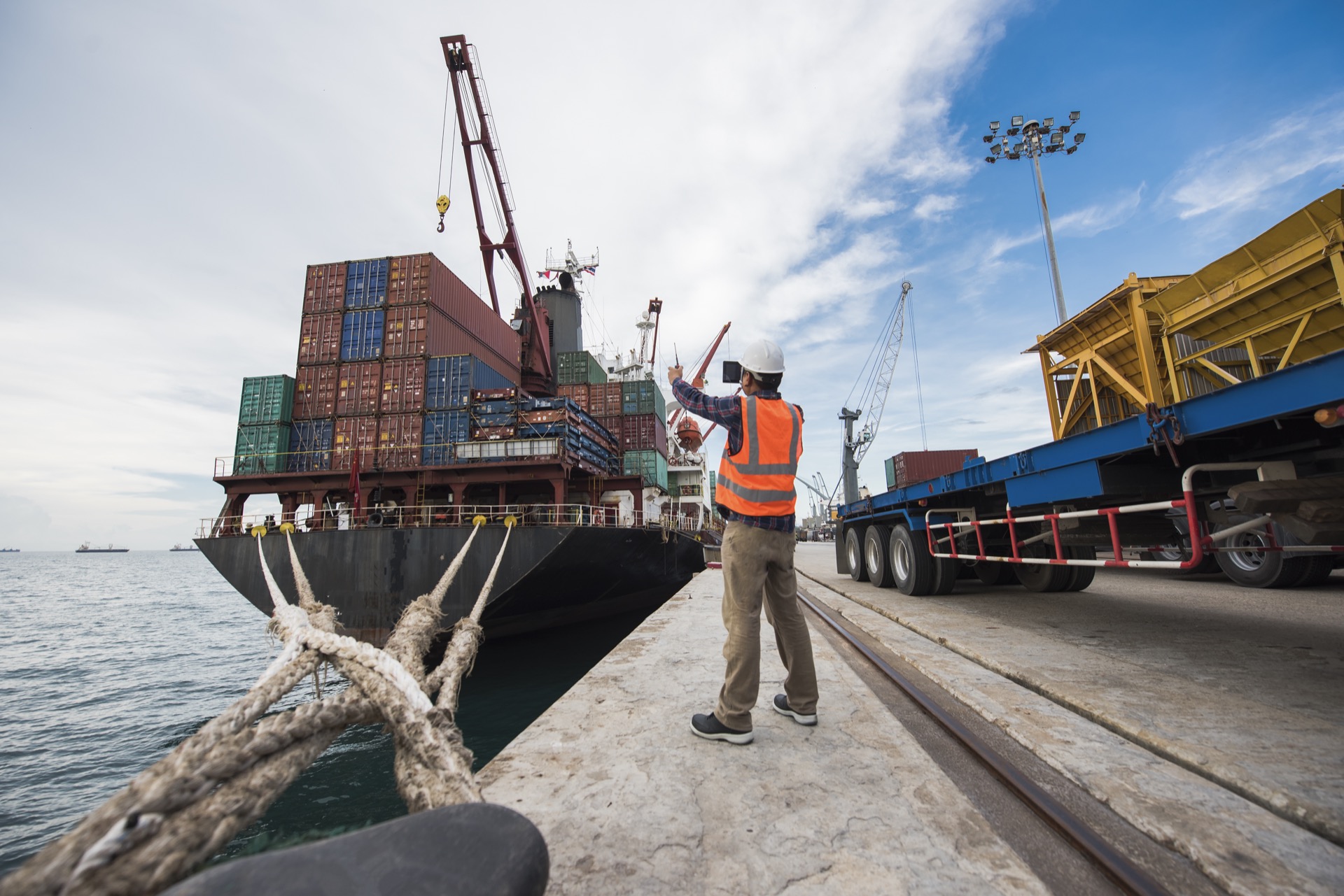 a worker in a hard hat directing a container ship into port