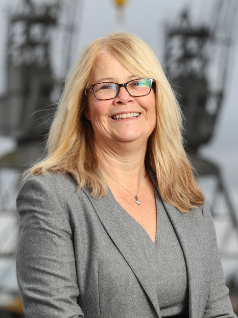 jan tomkins in a suit smiling at the camera