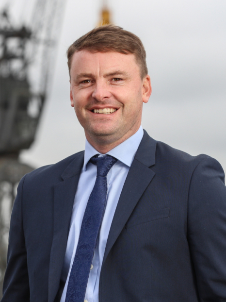 scott willmore in a suit smiling at the camera