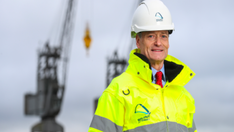 Man in high vis jacket with cranes in background