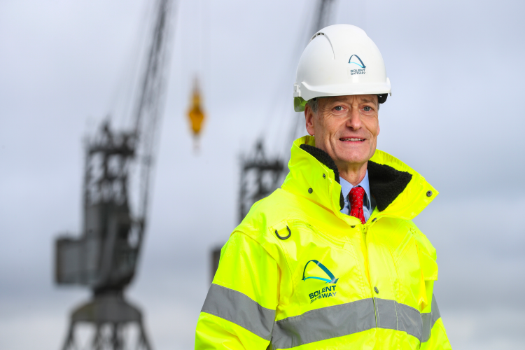 Man in high vis jacket with cranes in background