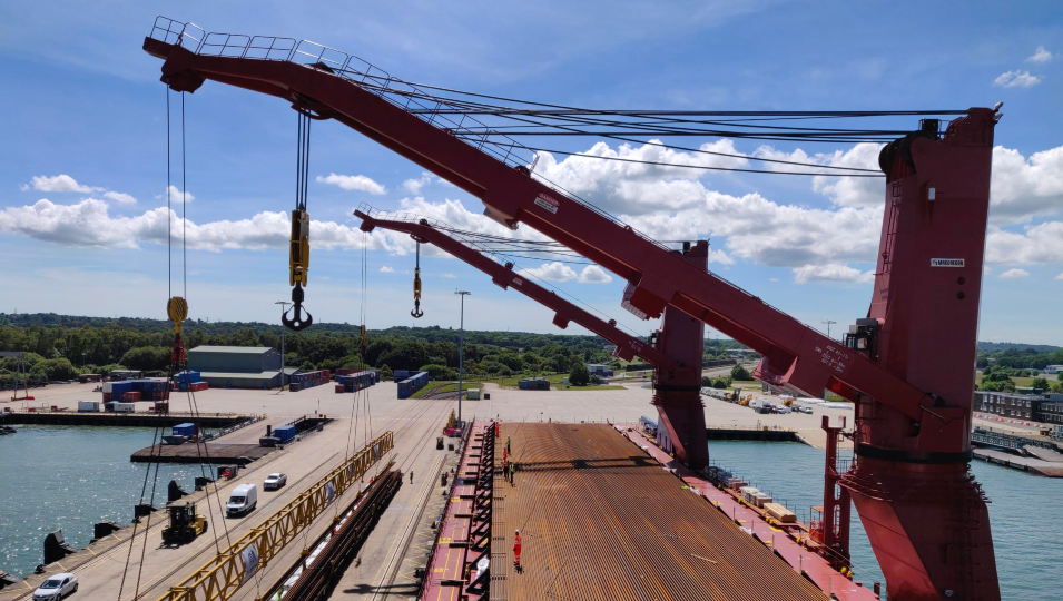 two red cranes above a container dock on a sunny day